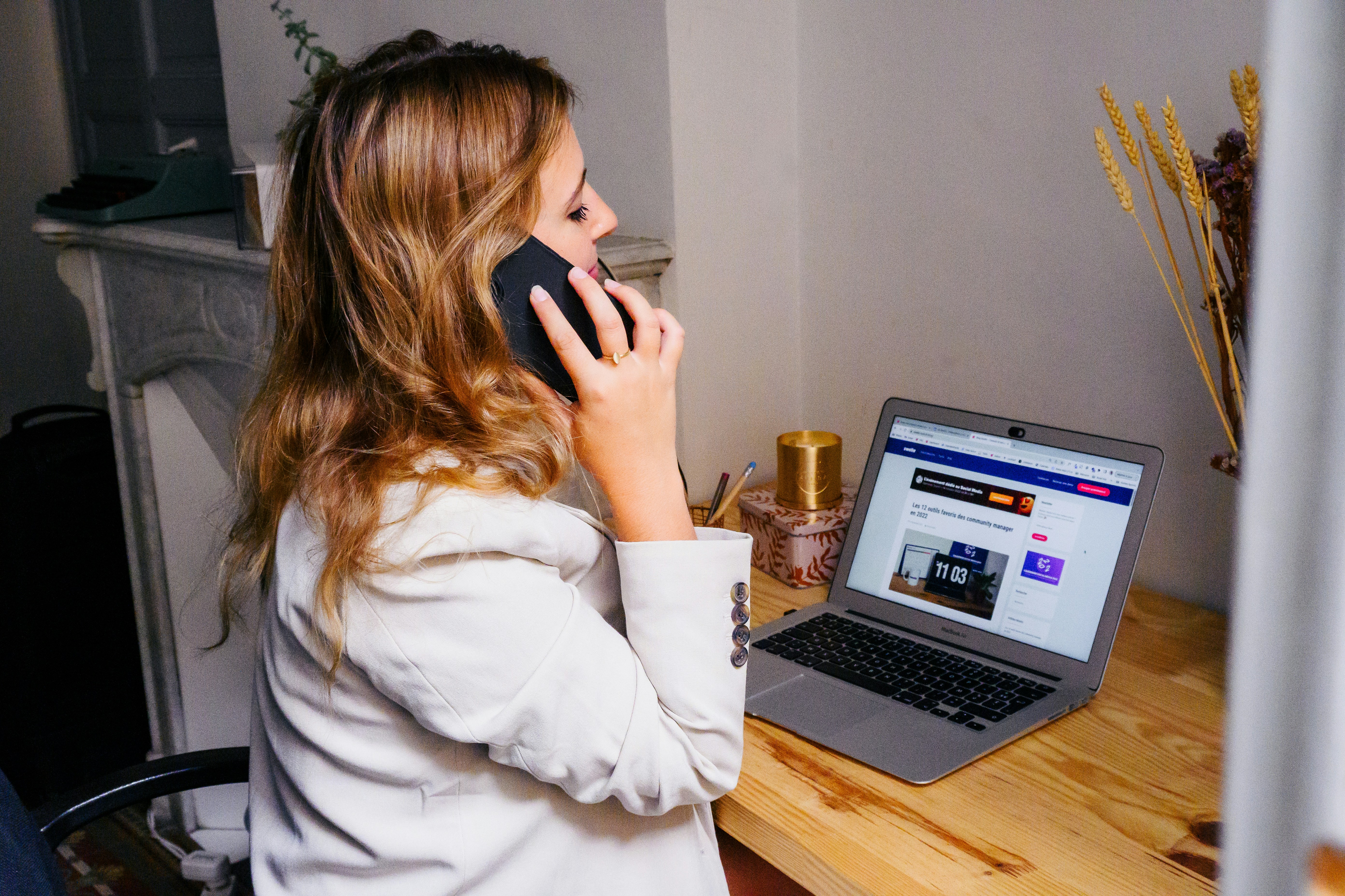 Woman speaking on the phone beside her laptop